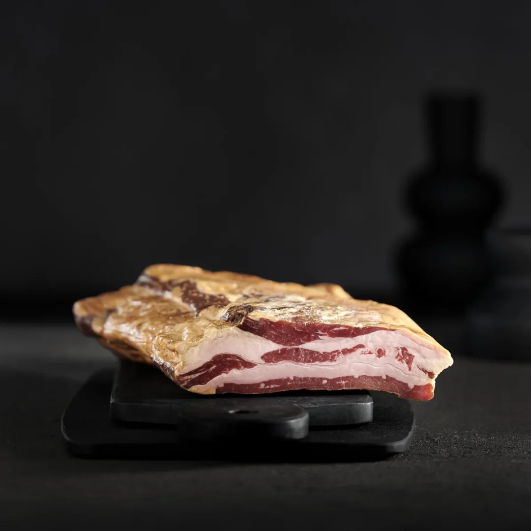 Tranches de pancetta halal de bœuf disposées sur planche en bois